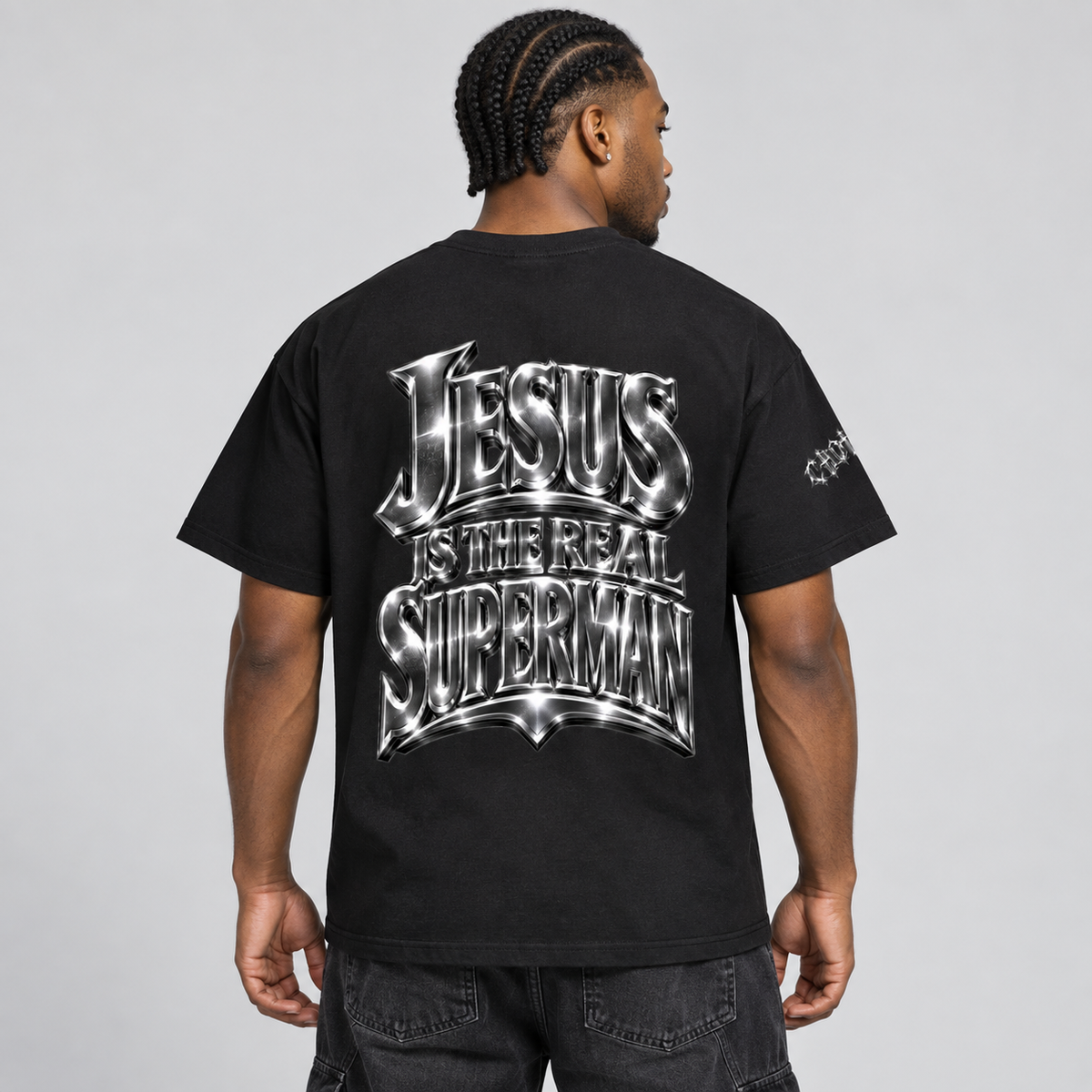 Back view of model wearing the black Jesus Is Super T-shirt, showing the rear graphic.