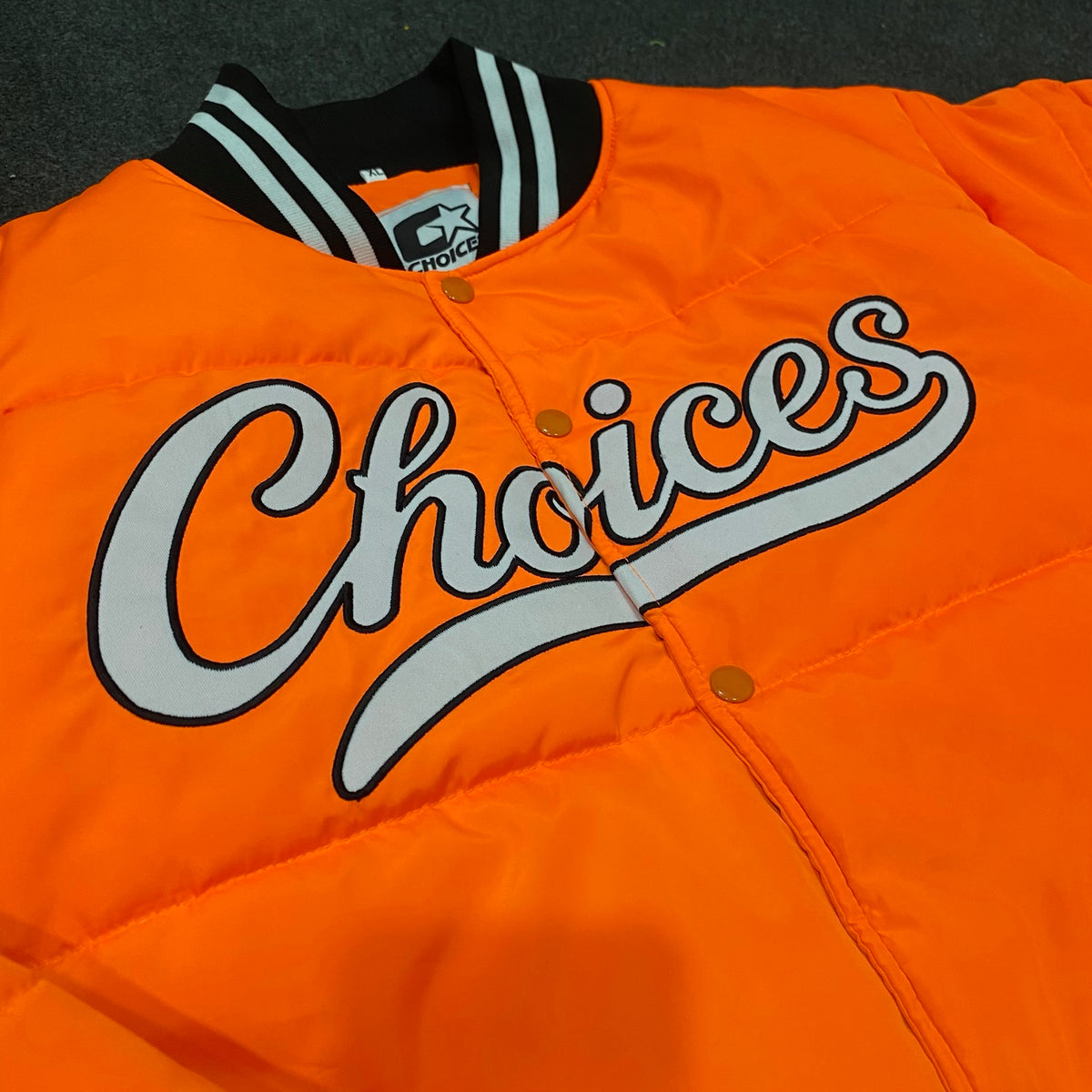 Close-up of Choices lettering on the orange Started Jacket